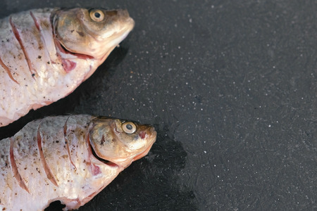 Carp in spices on a black table close-up. Top view.