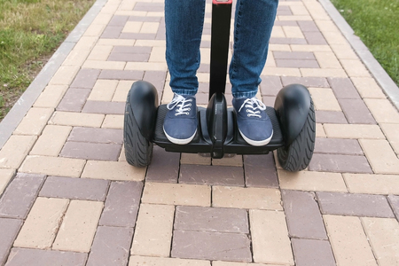 Persons legs in sneakers rolling on gyro scooter on paving road.の写真素材