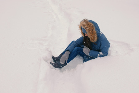 Woman has fallen in a snowdrift outdoor.