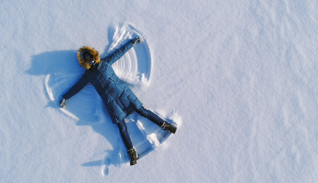 Woman makes snow angel laying in the snow. Top view. Aerial foto.の写真素材
