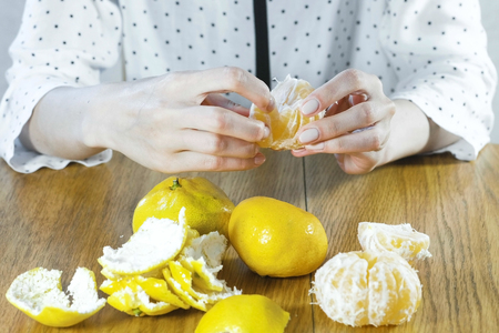 Woman peels a tangerine by hands. Hands close up.の写真素材
