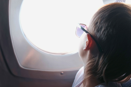 Boy looks out the window of the plane in sunglasses.の写真素材