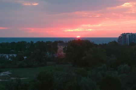 Sun at sunset over the sea in a coastal town. Pink sunset over the sea.