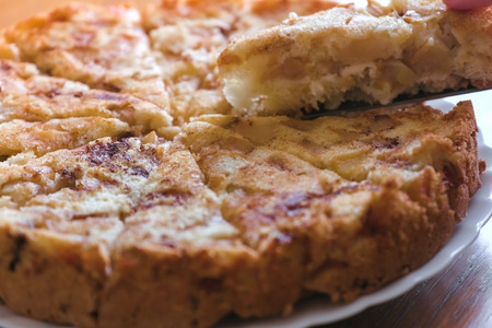 Close-up womans hands takes a slice of a homemade apple pie from plate.