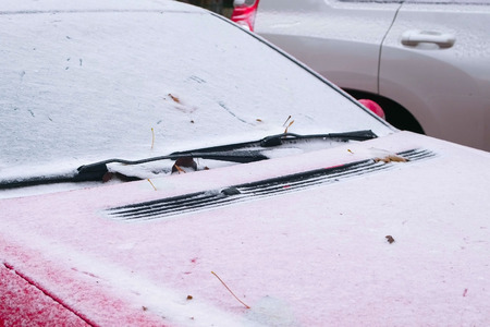 Frozen red car covered snow at winter day, view front window windshield and hood.の写真素材