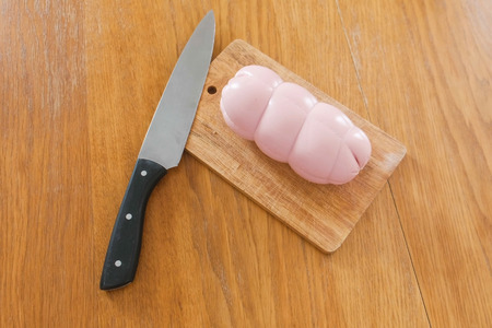Boiled sausage, knife and wooden Board on the table.