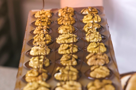 Halves of walnuts on the chocolate candies in the forms.の写真素材
