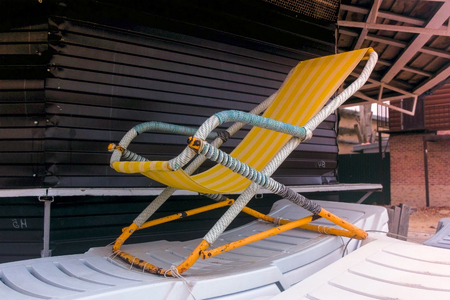 Plastic sun loungers on the sandy beach near the wooden house.の写真素材