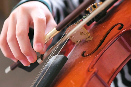 Violin in boys hands. Boy is learning to play violin. Correct setting of the fingers of the right hand on the strings of the violin.の写真素材