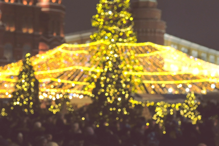 Crowded square with Christmas trees and decorations. Blur.