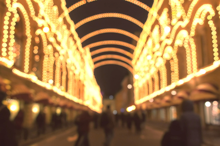 Beautiful building with arches in Christmas lights at night. People walking on the street in city. Blur.の写真素材