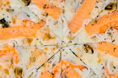Slicing pizza with seafood and cheese on wooden board, close-up viewの写真素材