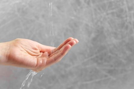 Water is pouring through the womans hand. Woman is trying to hold water in palm. Time concept. Hand...
