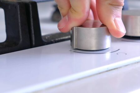 Man presses the rotary switch to turn on gas stove. Hand close-up.