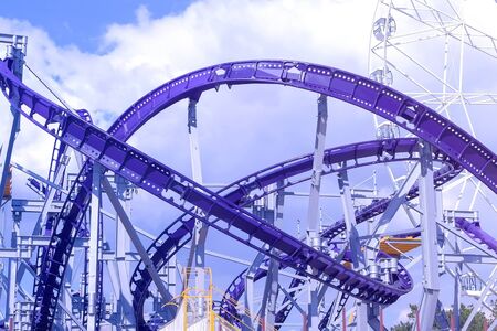 Roller coaster ride in the amusement Park on blue sky background and spinning Ferris wheel at Sunny day.の写真素材