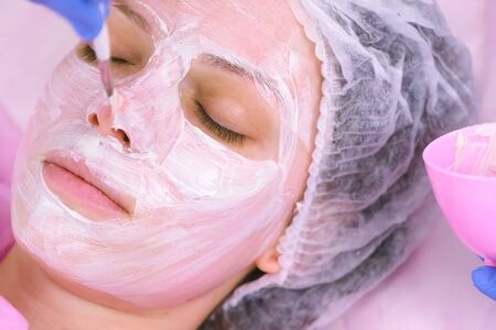 Cosmetologist puts mask on womans face with brush. Moisturizing faceの写真素材