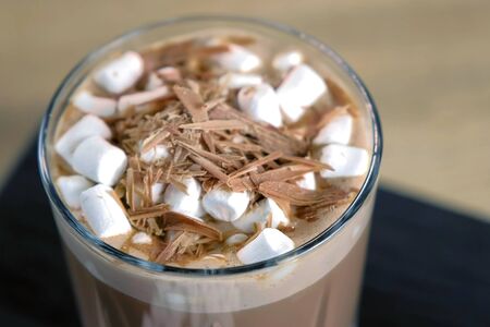 Cocoa with marshmallow in rock glass on a wood black tray. Close-up view