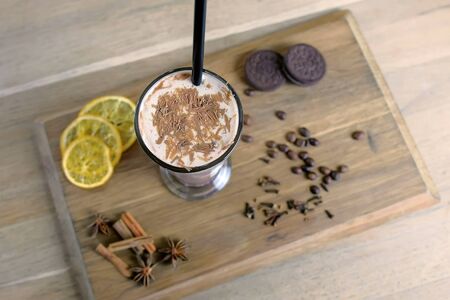 Irish coffee served on a wood tray with lemon, cookies and coffee beans. Close-up top view
