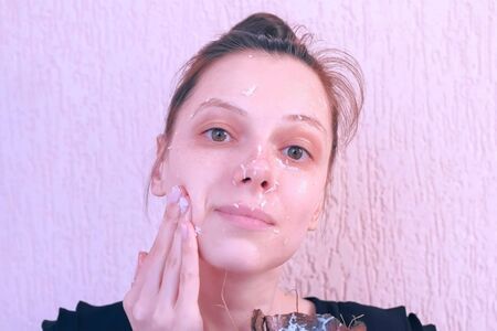 Portrait of young woman is applying fresh homemade coconut mask on the face from coconut shell. Natural organic cosmetics for skin care.の写真素材