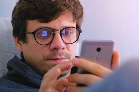 Man in glasses buy in online shop and browsing on smartphone. Face close-up. Online shoppingの写真素材