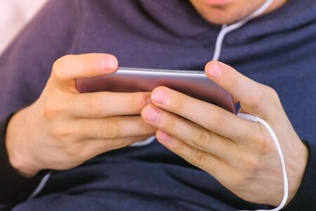 Man is playing a game in smartphone. Gamer relax. Hands close-up