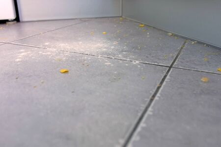 Dirty kitchen floor with food leftovers, flour, corn flakes after cooking. Close-up viewの写真素材