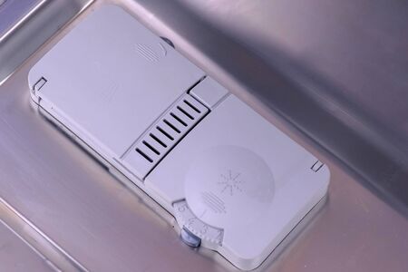 Detergent tablet in automatic compartment in dishwasher. Close-up top view.