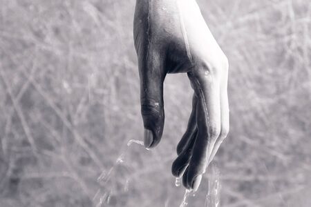 Water is flowing through the womans hand. Hand close-up. Time concept. Black and white.の写真素材