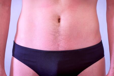 Man in balck underpants is straining his press after training. He hopes to see abs muscles, closeup view. Newcomer in sport.の写真素材