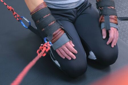 Tied hands and feet legs with ropes of sportsman preparing for myofascial stretching in gym, closeup view. Stretch muscles, ligaments, tendons. Professional sport fitness trainer equipment mashine.の写真素材