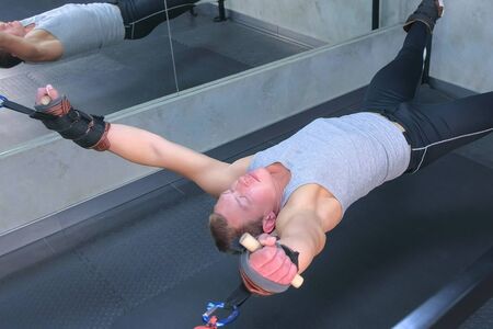 Sportsman making exercises in air uses trainer for myofascial stretching in gym. Recovery...