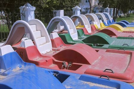 Colored catamarans on the waterfront near the sea along the fence. Catamaran rental for tourists. River and sea transport for recreation activity outdoor.の写真素材