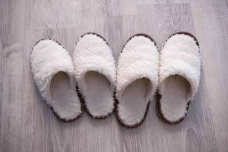Two pairs of white slippers from sheep wool on the floor, closeup view.の写真素材