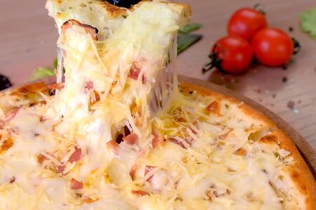 Cook takes a slice of pizza with a gloved hand. Hand close-upの写真素材