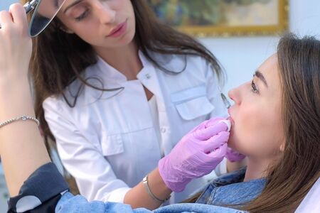 Cosmetologist explains woman how to care about lips after injection. Beautician talking about...