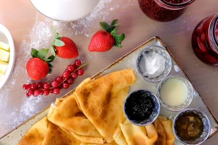 Traditional russian pancakes, blini. Served with jams, sour cream, milk and strawberry on the plate. Top viewの写真素材