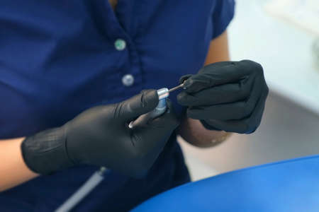 Dentist is preparing dental drill machine to work inserting the cleaning nozzle in stomatology...