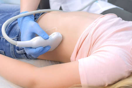 Doctor making abdominal ultrasound for child girl using scanner, closeup view, tummy and hands...