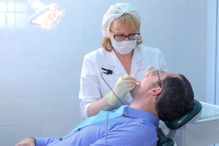 Dentist examining gums of patient with a probe and needle using method of computer diagnostics. Measuring depth of periodontal pockets and assessing state of gums in stomatology clinic, dentistry.の写真素材