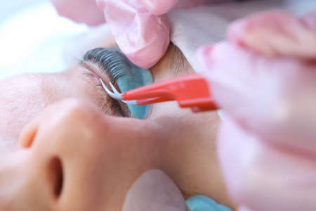 Cosmetologist bending lashes with needle into curlers, lift eyelashes laminaton procedure in beauty...