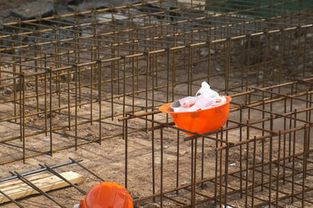 Ground floor of building under construction waits for concrete slab pouring. Rusty metal wiring is...
