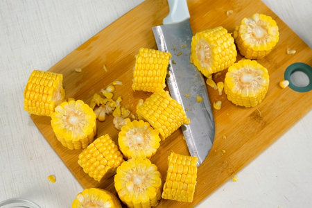 Cook, prepare, cut on pieces yellow fresh corn on wooden board on kitchen. Cuisine culinary preparing cooking dish domestic food recipe ingredients. Healthy nutrition eating with vegetables.の写真素材