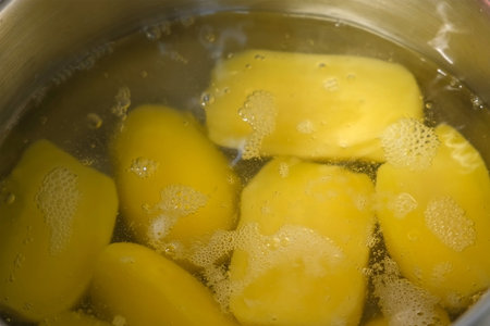 Potatoes in boiled water in saucepan, cooking dish at home on kitchen, close-up view. Cuisine, culinary, prepare cook domestic food, recipe, raw organic vegetables ingredients, products concept.の写真素材