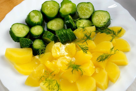 Prepared served dish with boiled potatoes, butter, pickles decorated fresh dill in white plate, close-up view. Culinary, prepare cook, domestic food, recipe, fresh ingredients, products.の写真素材