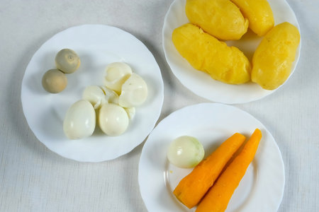 Ingredients for salad, dish, cooking food eggs, vegetables on plates on kitchen. Boiled potatoes, carrots, fresh pilled onion, eco healthy products for recipe. Cuisine, culinary concept.の写真素材