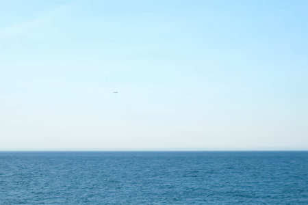 Airplane plane flying over the sea in clear blue sky at sunny weather. Passenger jet approaching to...