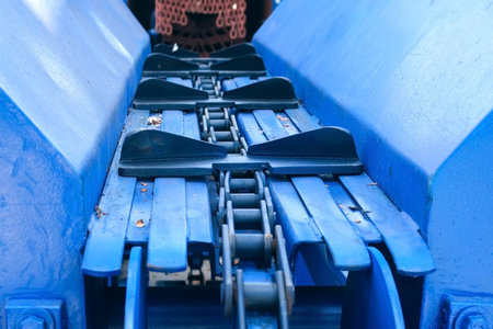 Blue industrial conveyor belt for moving logs from wood debarking machine. Modern equipment for...