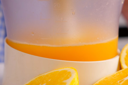 Squeezing oranges tangerines juice using electric juicer in kitchen at home. Healthy vegan ripe...