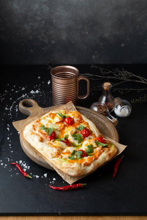 Pizza with mozzarella cheese, tomatoes and herbs on a black backgroundの写真素材