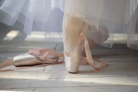 Ballerina putting on pointe shoes on a wooden floor.の写真素材